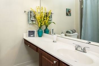 a bathroom with a sink and a mirror and yellow flowers